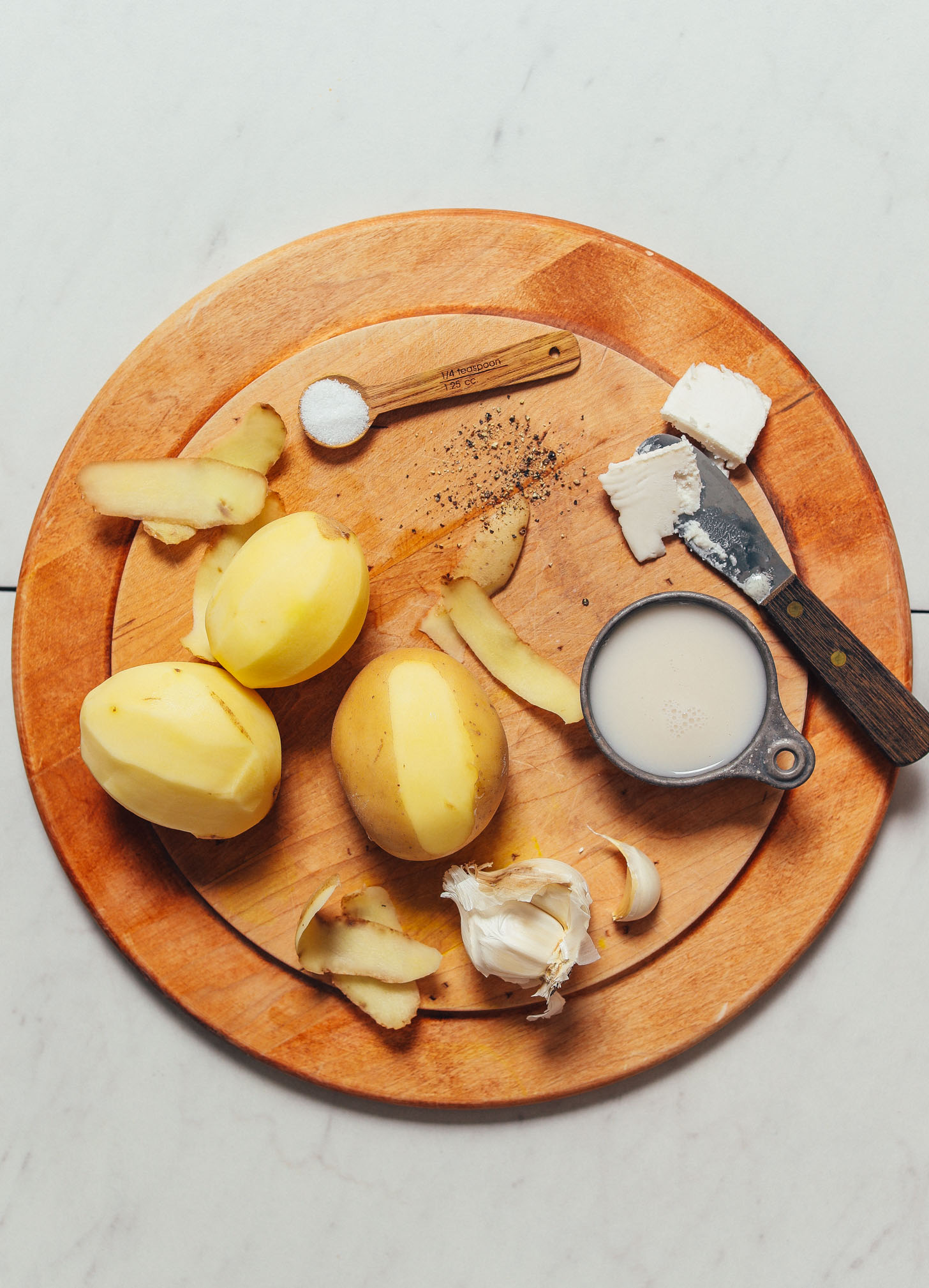 Wood cutting board with ingredients for making our vegan Mashed Potatoes recipe