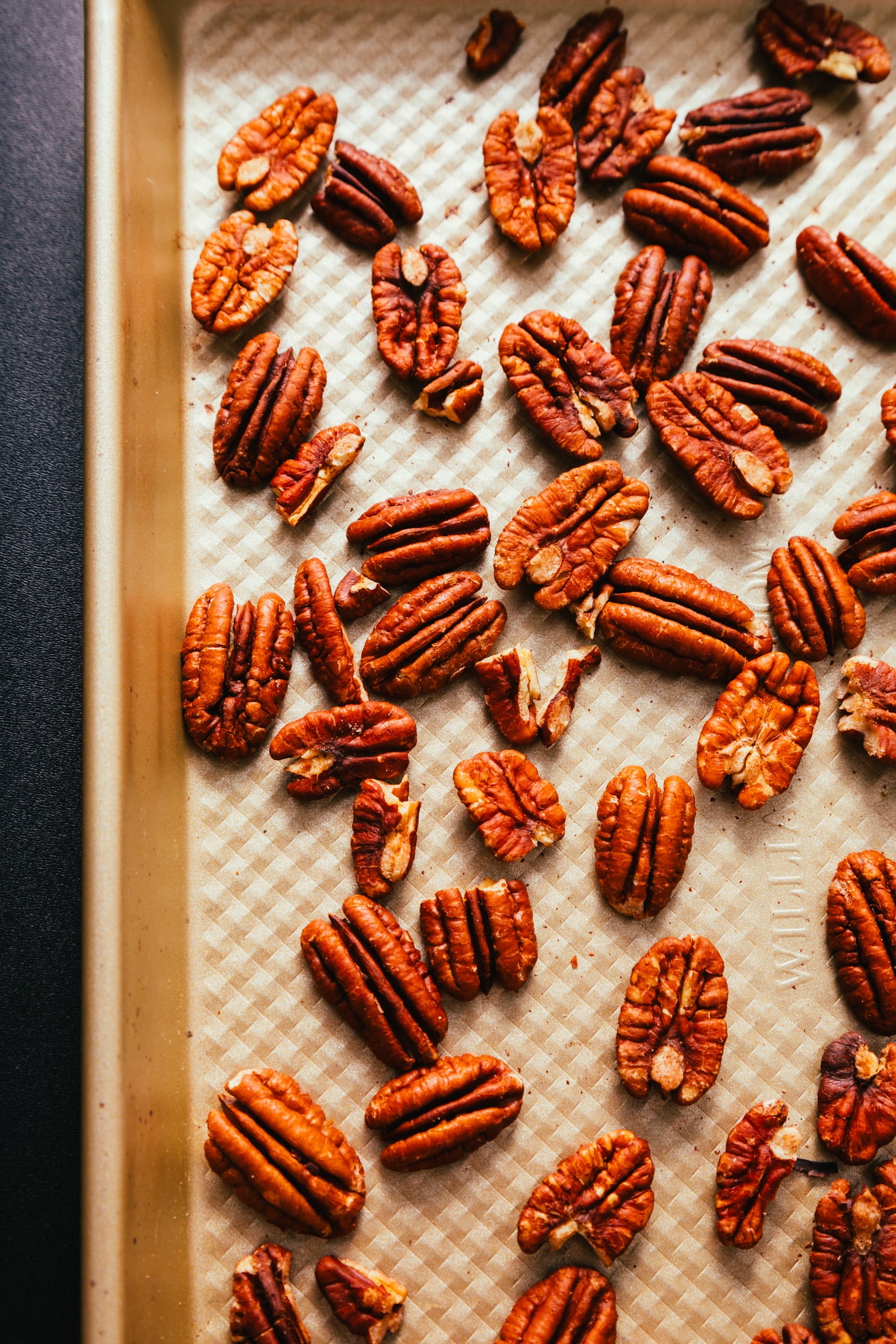 Toasting pecans on a baking sheet to make our Turtle Candies recipe