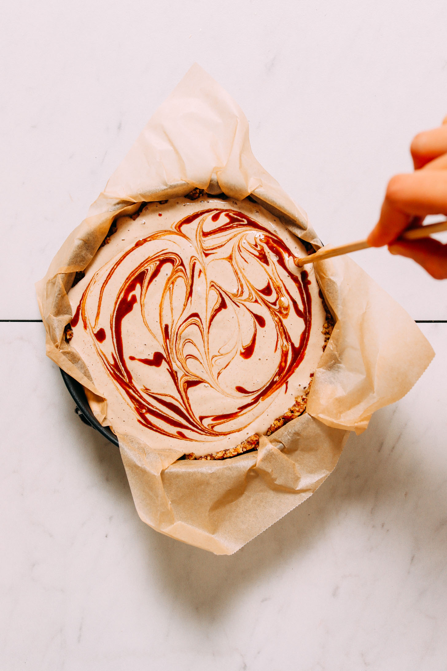 Using a toothpick to add caramel swirl to Vegan Chai Cheesecake