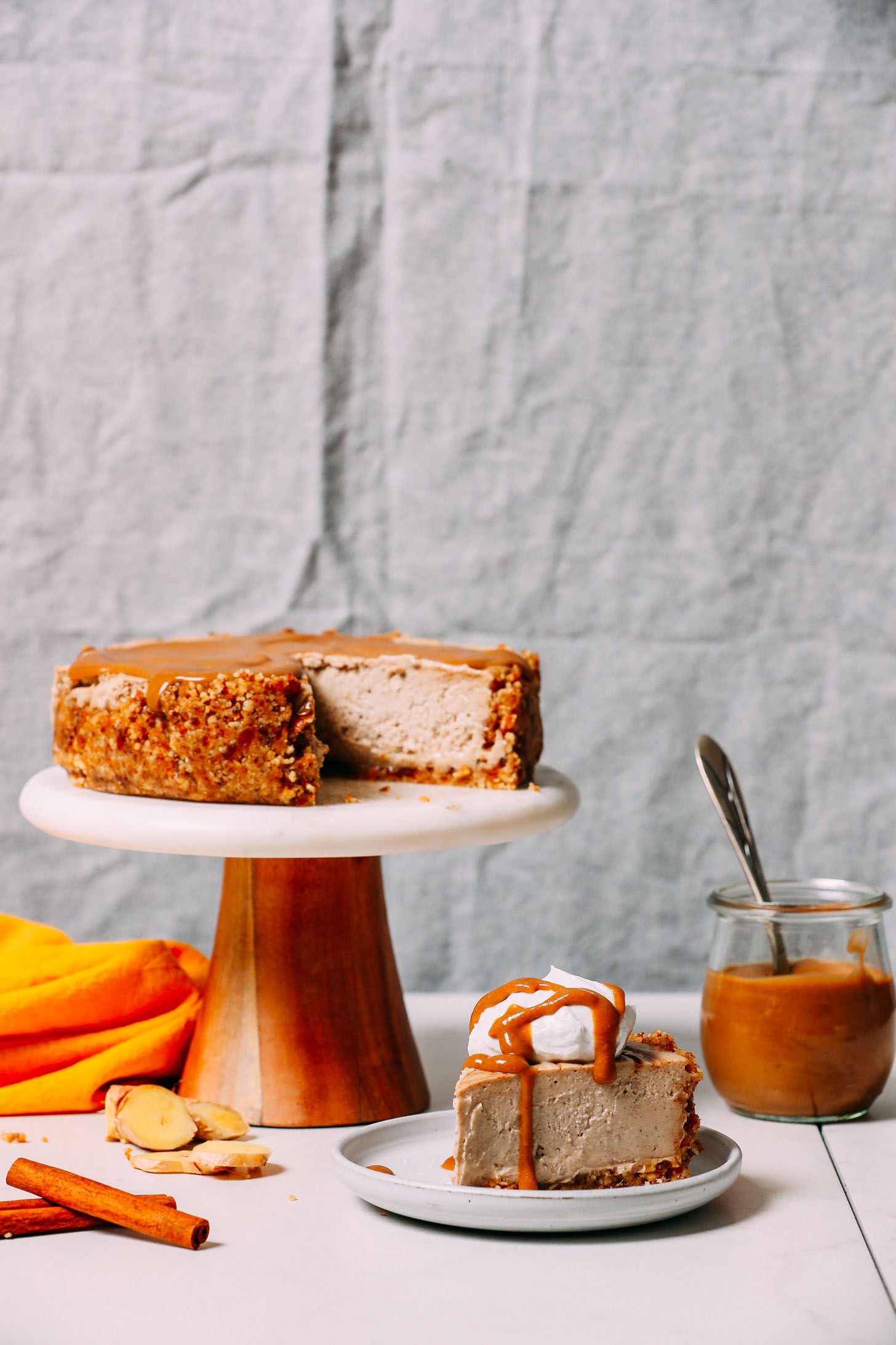 Slice of Vegan Chai Cheesecake topped with coconut whipped cream and a caramel drizzle