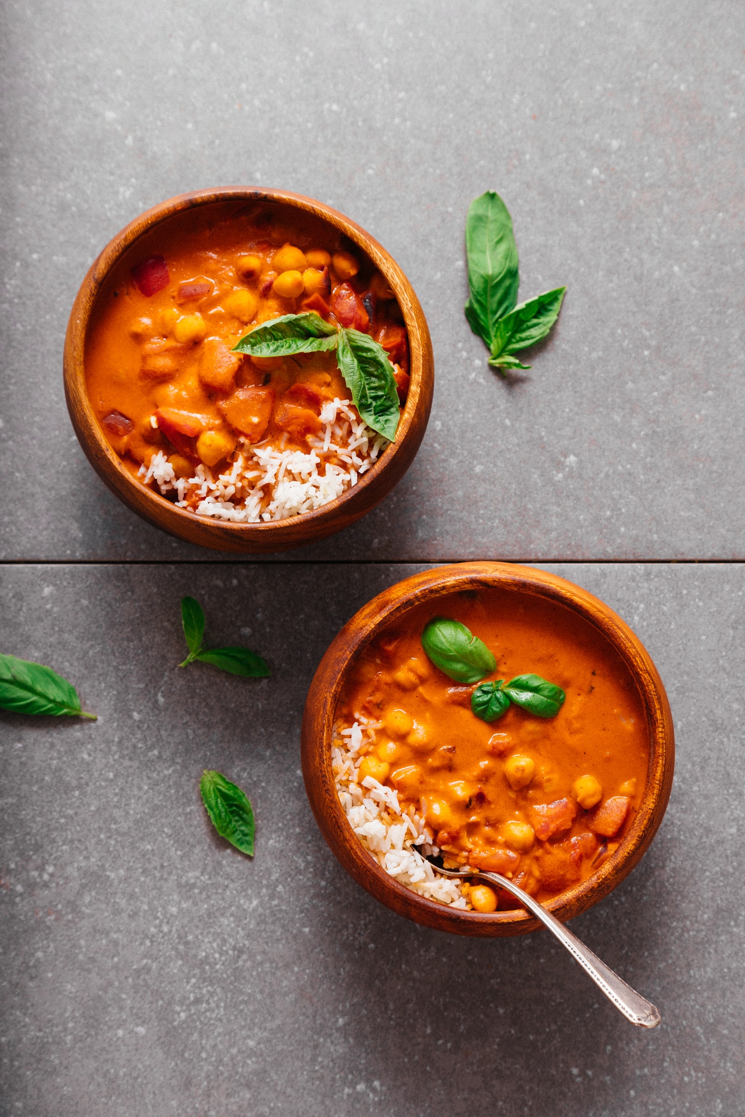 Two bowls of our 1-Pot Chickpea Tomato Peanut Stew recipe topped with fresh basil