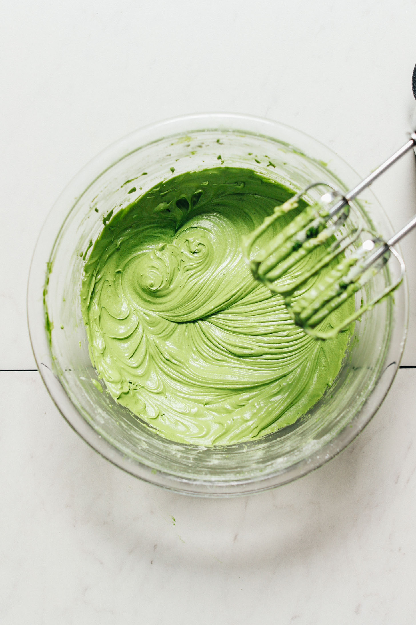 Hand mixer blades over a bowl of Vegan Matcha Frosting