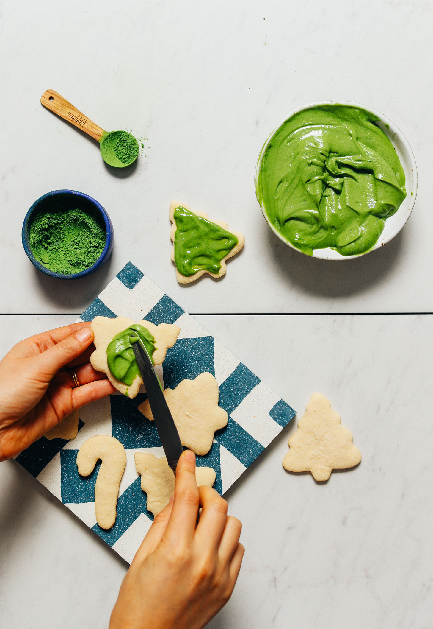 Spreading vegan frosting made with matcha onto a sugar cookie