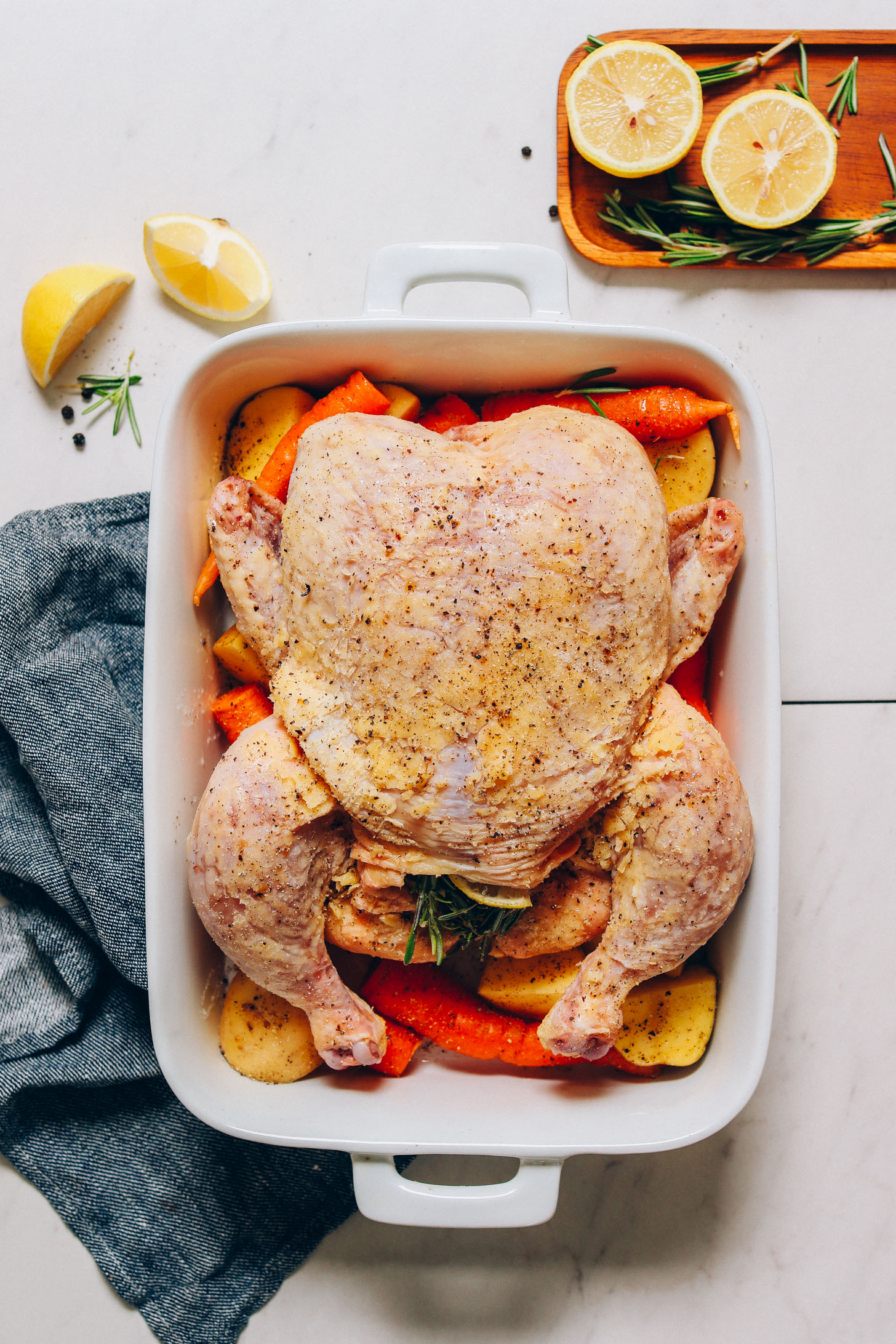 Ceramic pan filled with root vegetables and a seasoned chicken ready to go in the oven