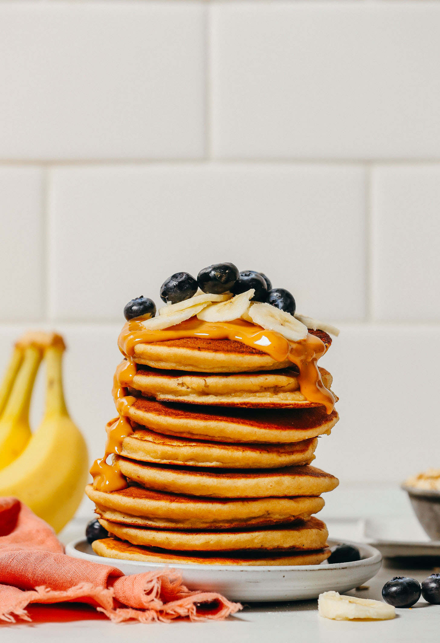 Stack of Blender Banana Pancakes topped with peanut butter and fresh fruit