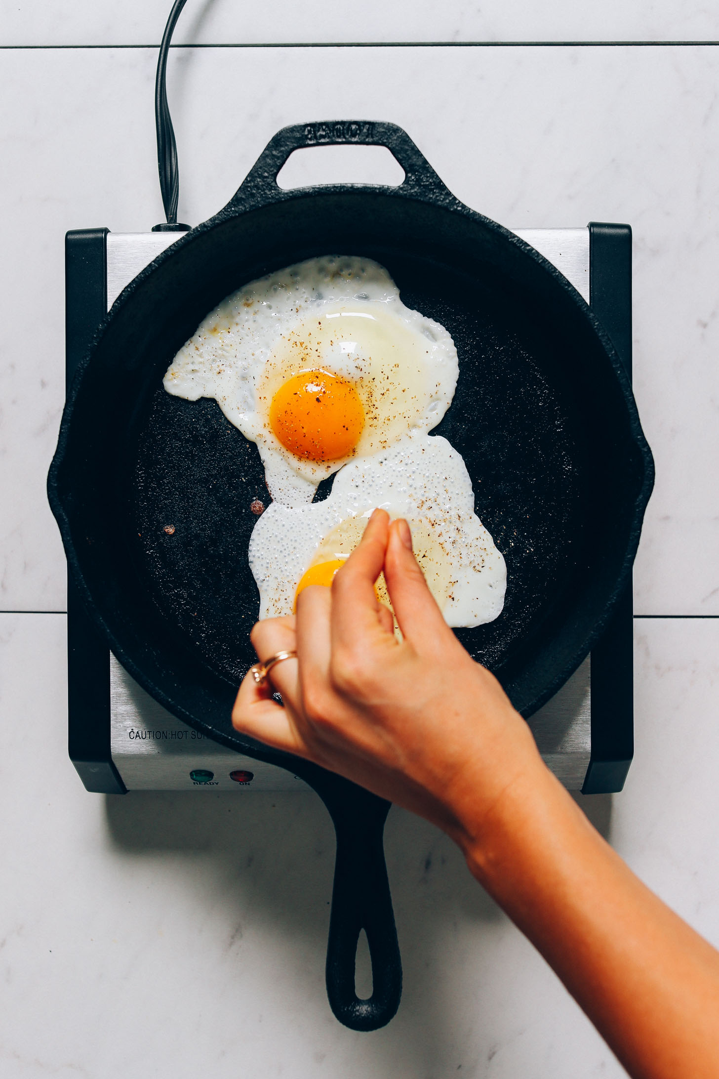 Sprinkling black pepper onto fried eggs for our How to Cook an Egg recipe