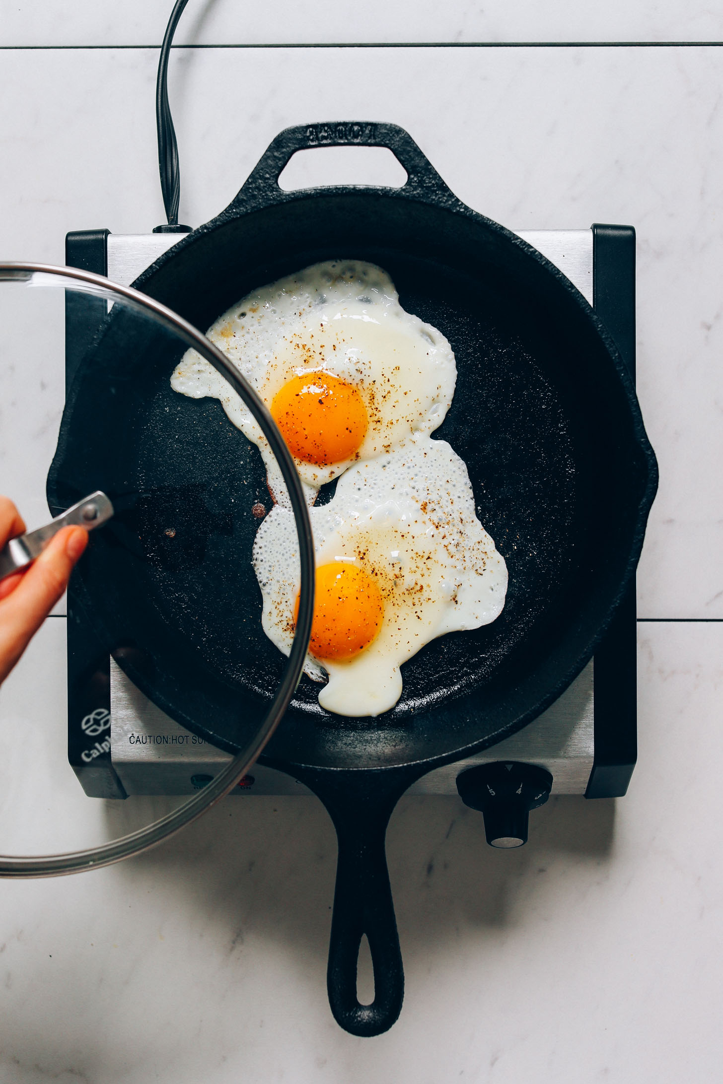 Covering fried eggs with a lid to make Perfect Sunny Side Up Eggs