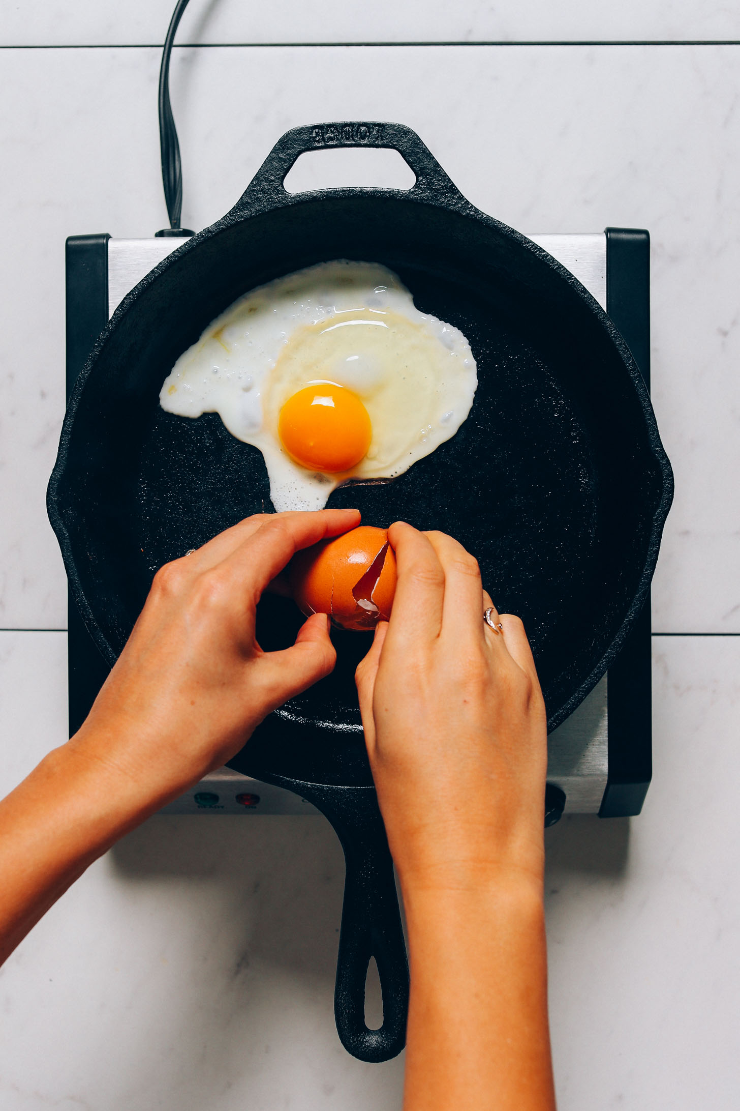 Cracking an egg in a skillet for our tutorial on How to Cook and Egg Perfectly Every Time