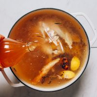 Pouring apple cider vinegar over a chicken carcass for our Chicken Bone Broth recipe