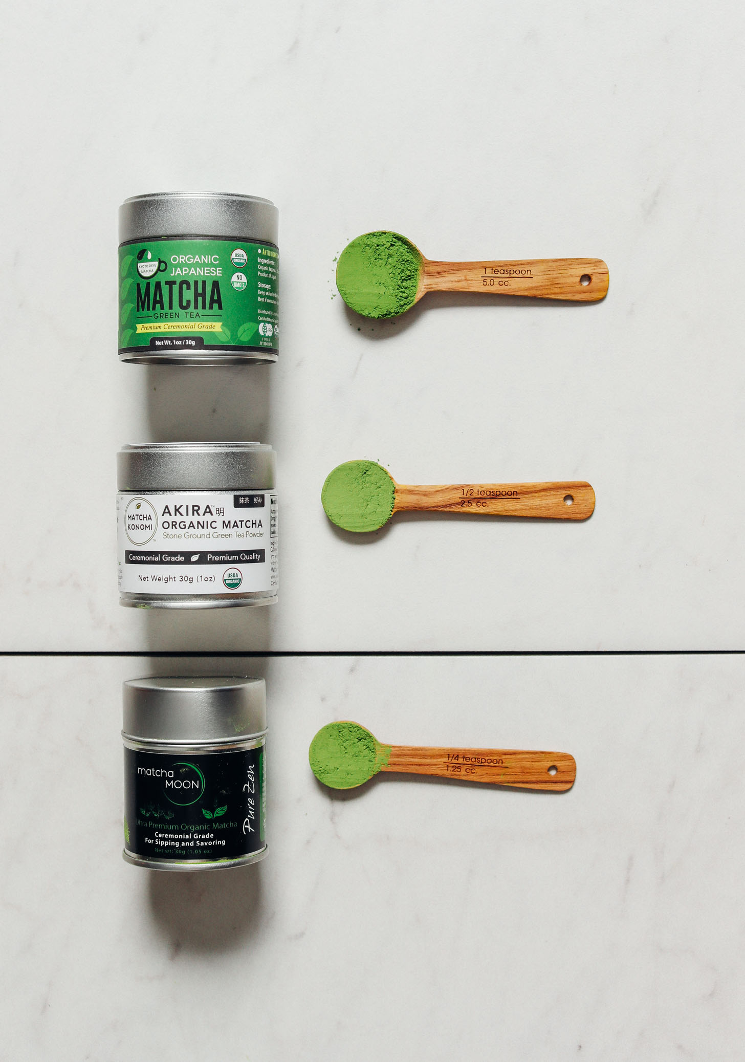 Spoonfuls of our top three favorite matcha brands beside their canisters
