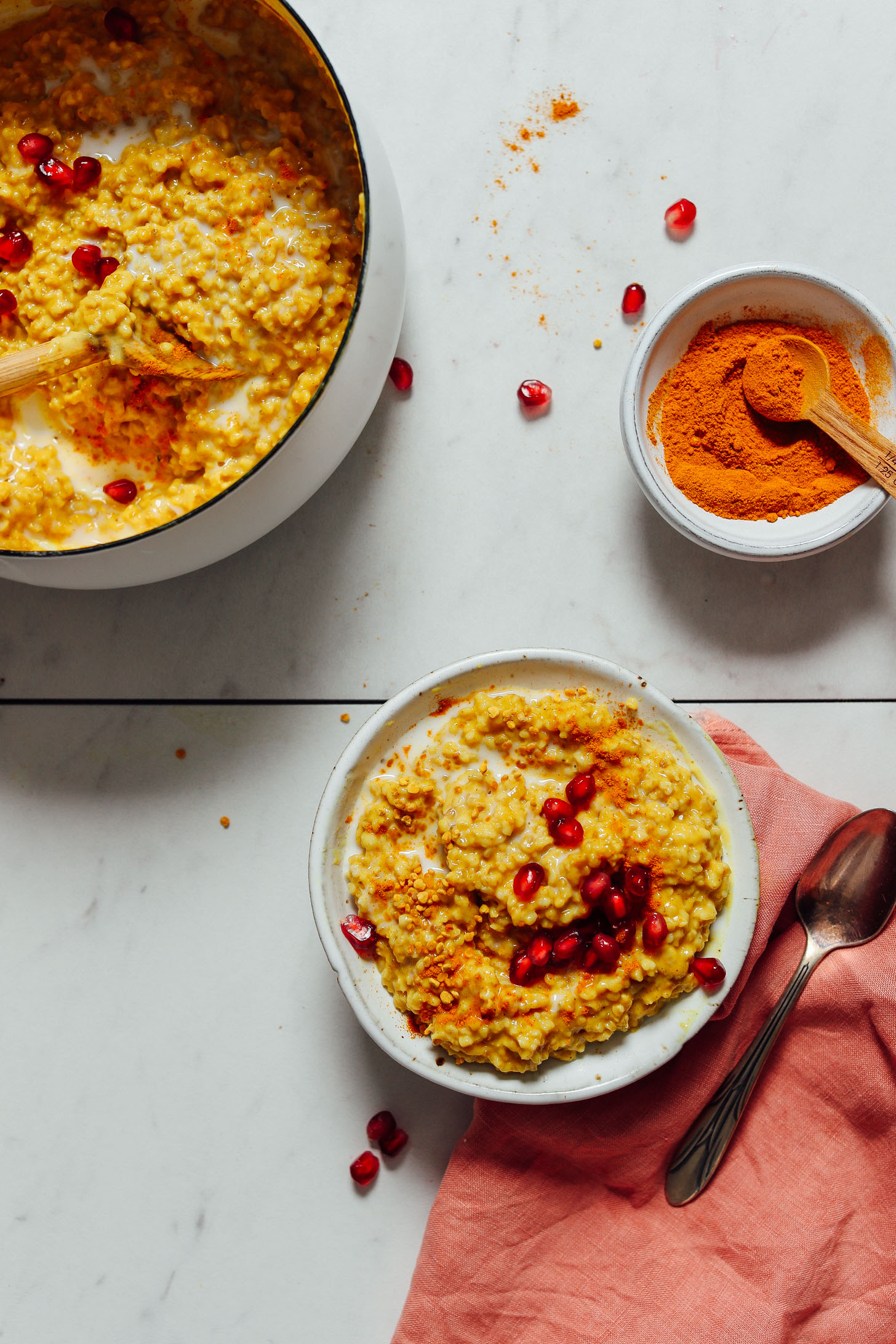 Bowl of turmeric beside a pan and bowl of our Cozy Turmeric Porridge recipe