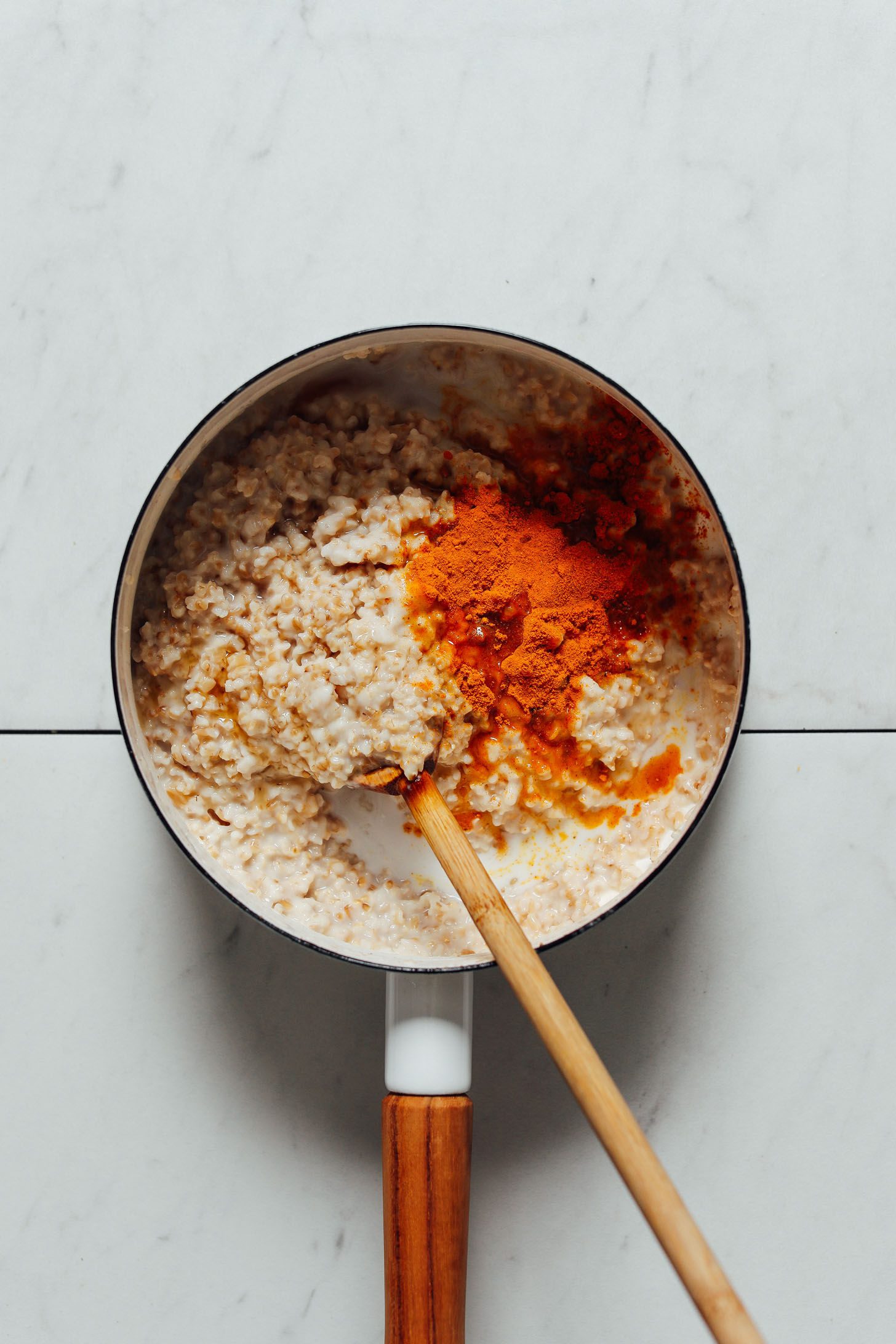 Wooden spoon in a saucepan of our Turmeric Porridge recipe