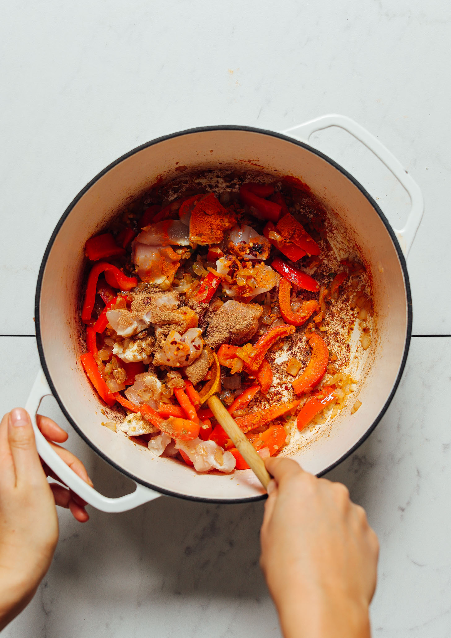 Using a wooden spoon to stir a pot of our dairy-free Tikka Masala recipe