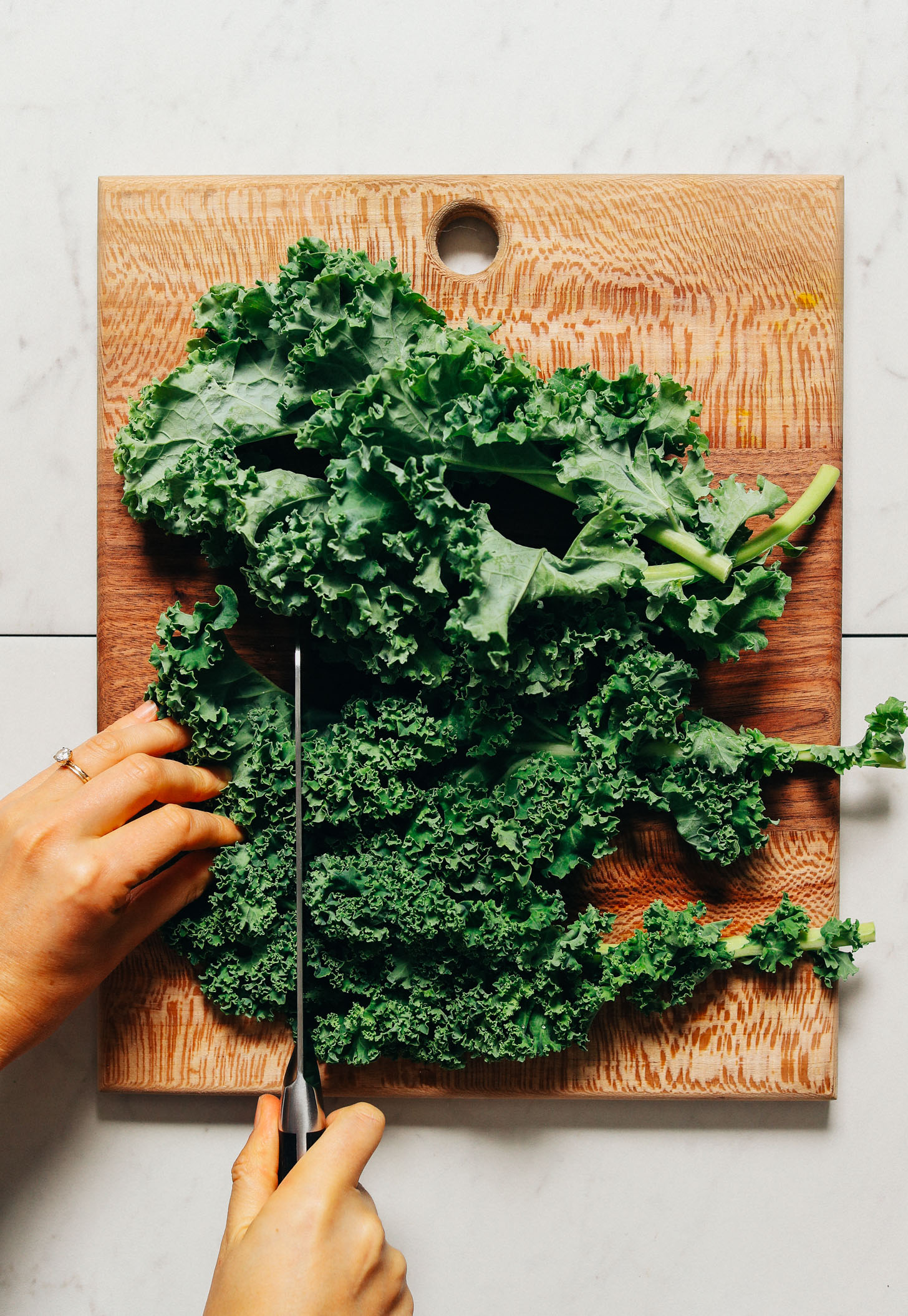 Using a large knife to chop kale for our Massaged Kale Salad recipe
