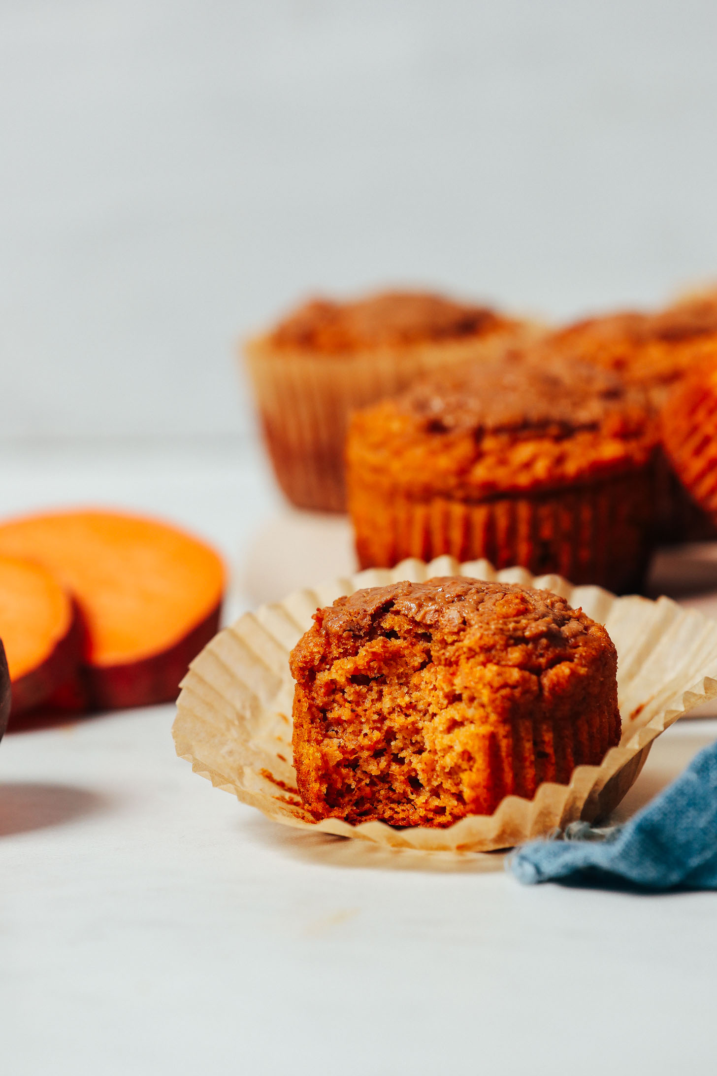 Partially eaten Almond Butter Sweet Potato Muffin beside sliced sweet potato rounds
