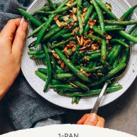 Holding a spoon in a big bowl of Garlicky Green Beans with Slivered Almonds