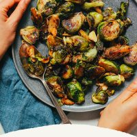 Holding a plate of Miso-Glazed Brussels Sprouts with recipe text below it