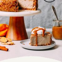 Slice of Vegan Chai Cheesecake resting on a plate beside the rest of the cake
