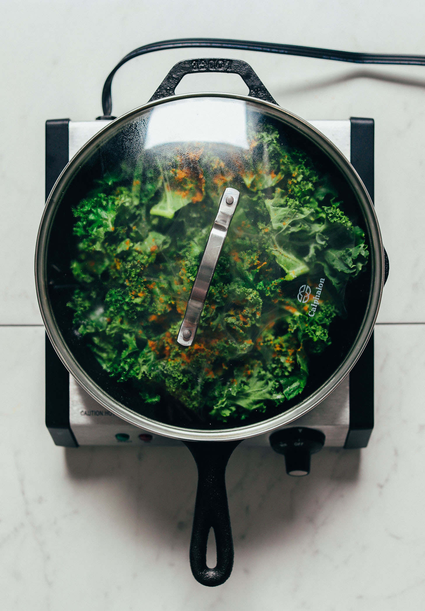 Covered pan of kale with curry powder for our simple Sautéed Kale recipe