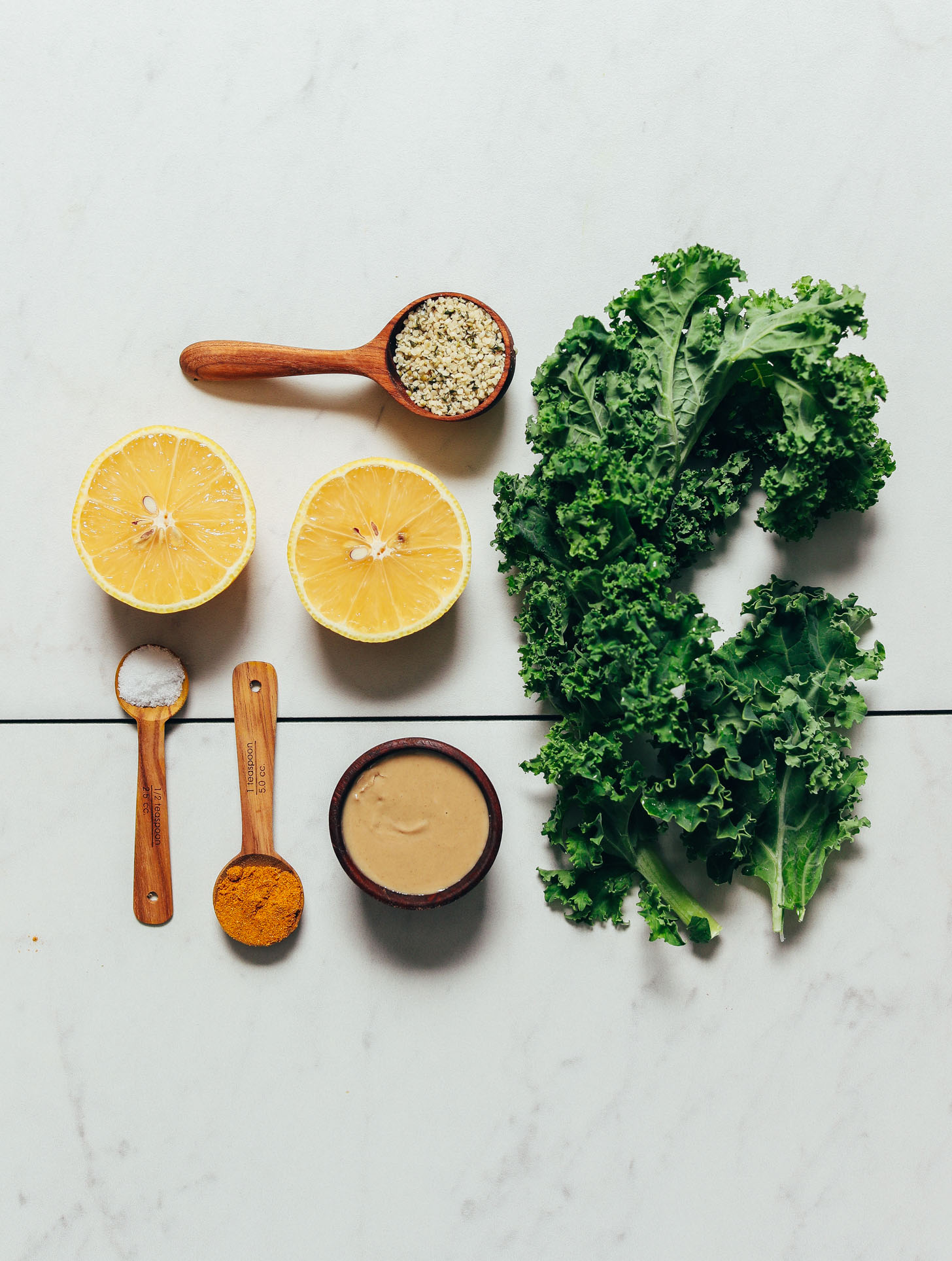 Kale, hemp seeds, lemon, tahini, curry powder, and salt for making our easy sautéed kale recipe