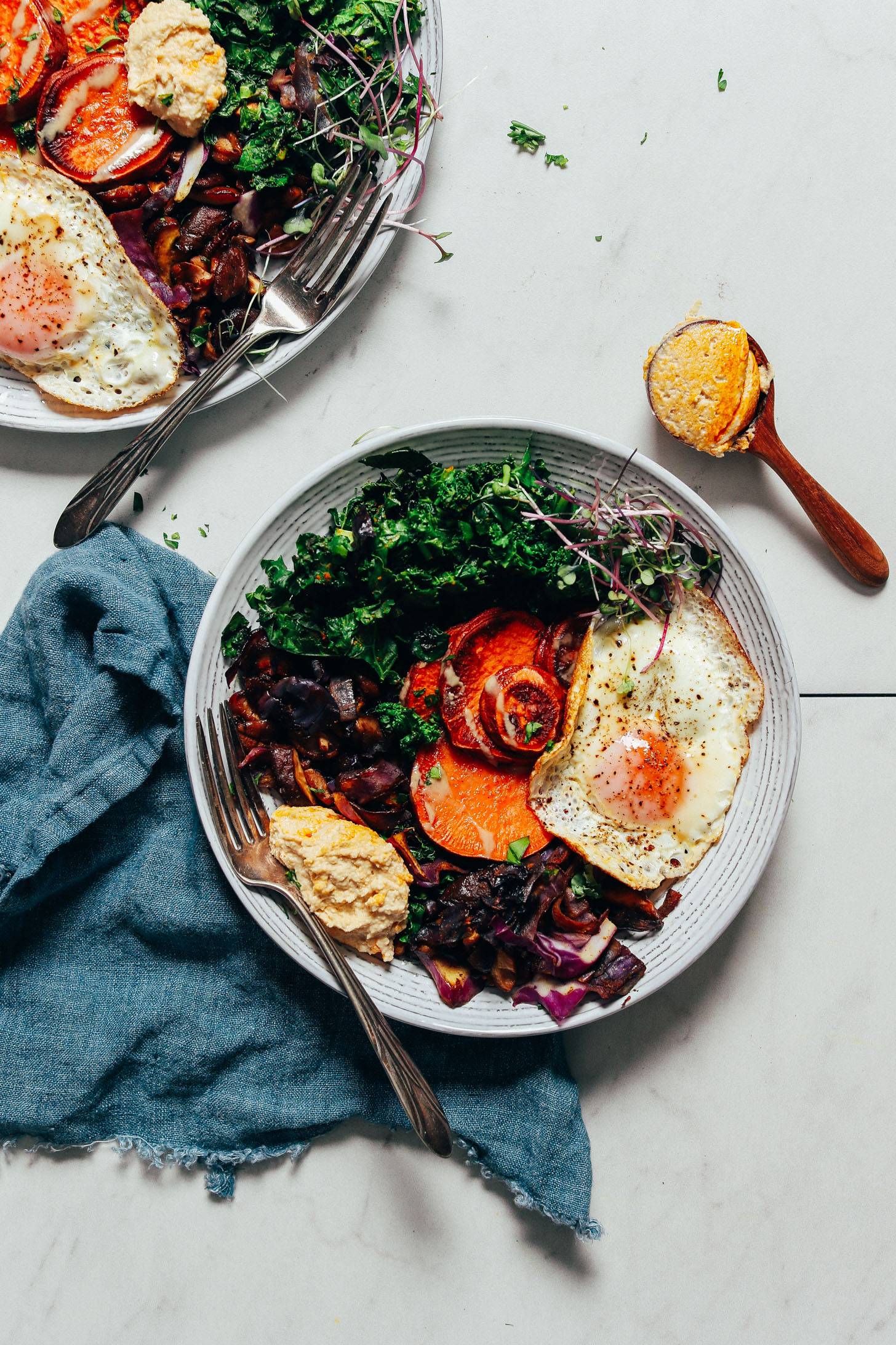 Spoonful of hummus beside Simple But Good Breakfast Bowls made with tons of veggies