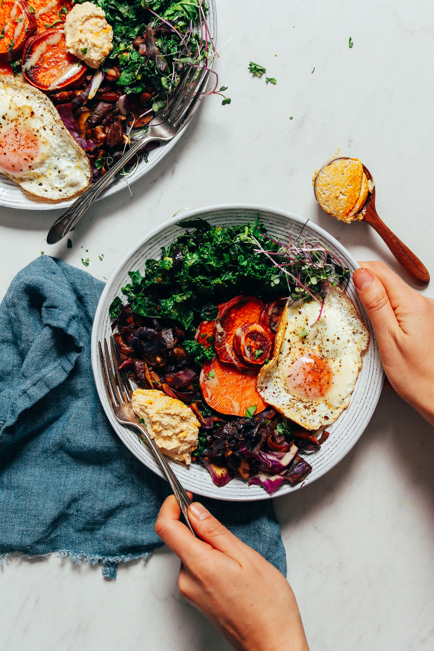 Holding a Breakfast Bowl filled with mushrooms, kale, cabbage, eggs, and sweet potato