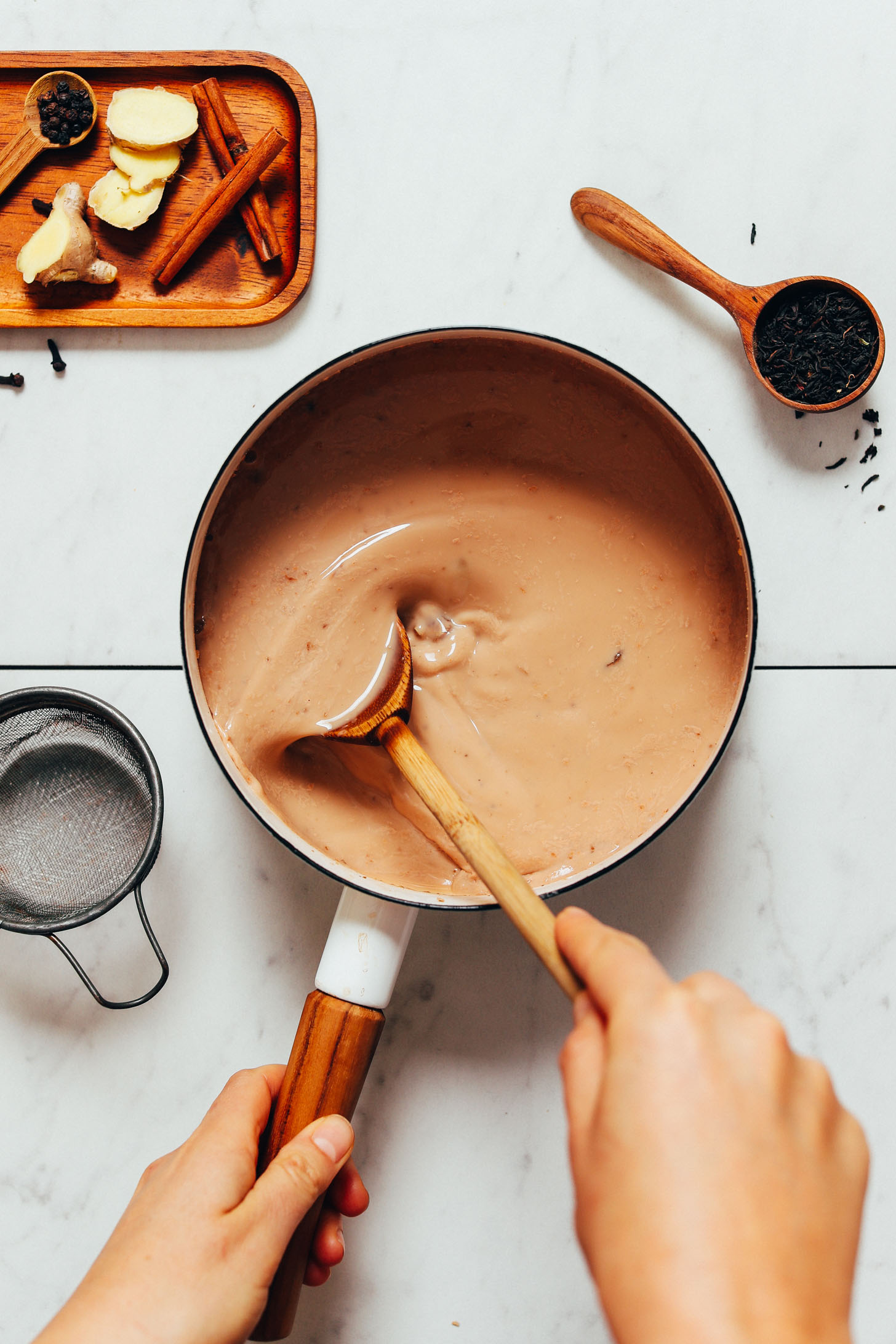 Using a wooden spoon to stir a pot of our Easy Masala Chai recipe