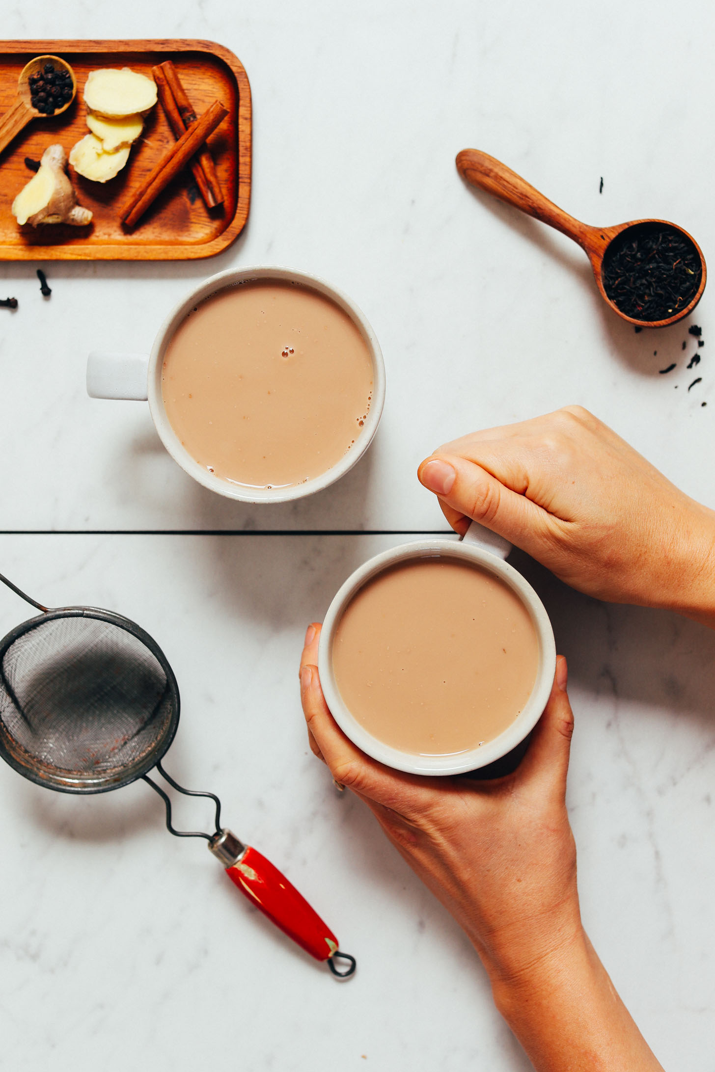 Holding a mug of homemade Masala Chai Tea next to ingredients used to make it