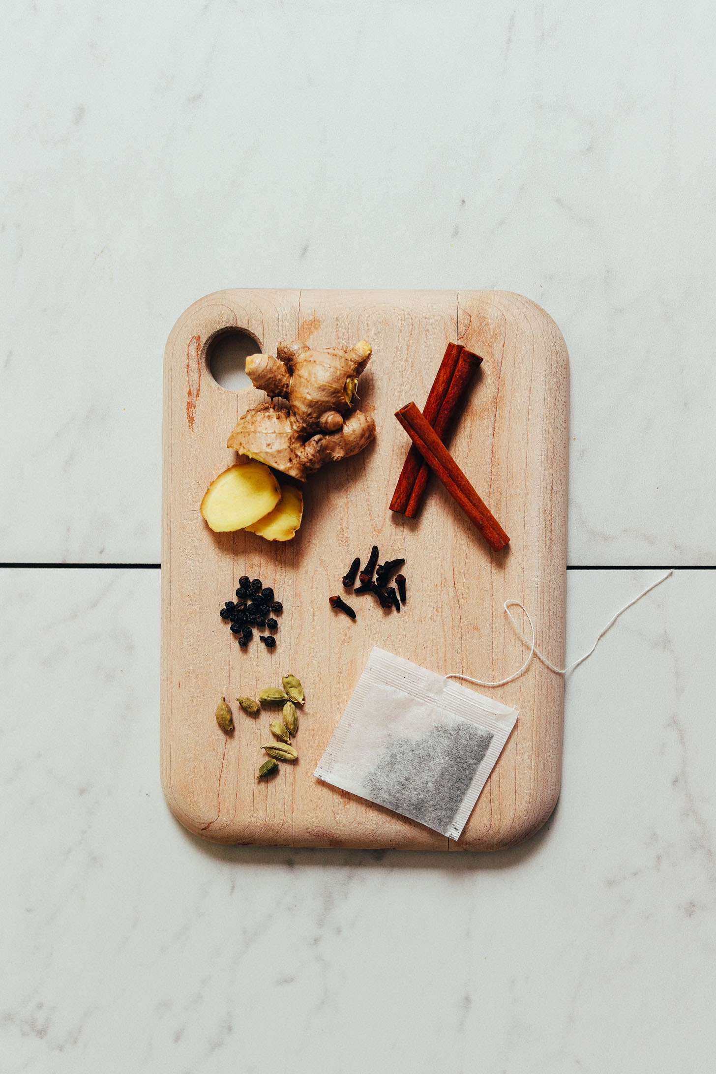 Ginger, cinnamon sticks, cloves, black pepper, cardamom pods, and black tea for making our homemade Chai Tea Recipe