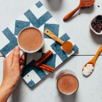 Holding the handle of a mug of vegan Hot Chocolate made with adaptogens