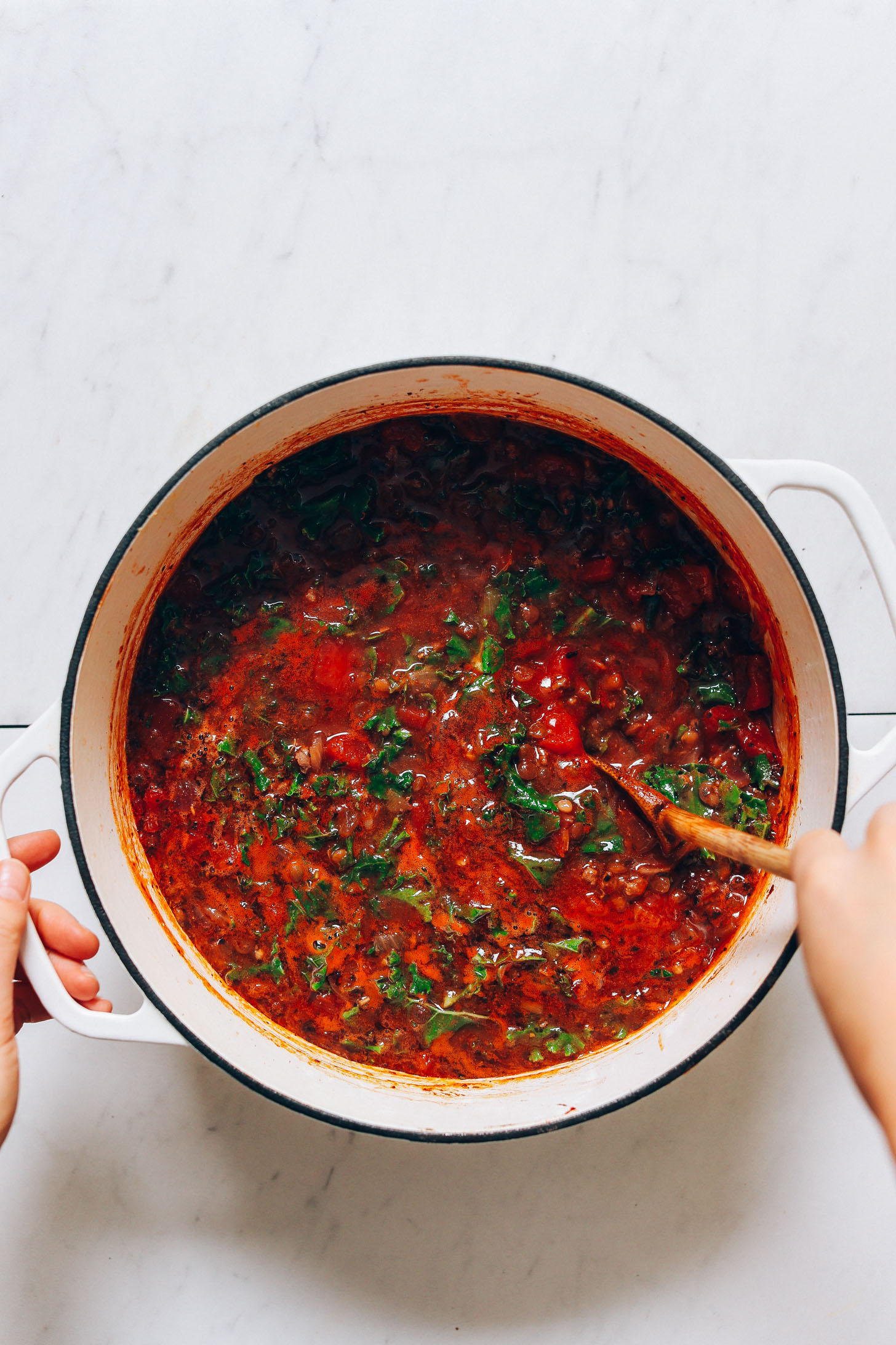 Stirring fresh kale into a pot of our Tuscan Beef & Lentil Soup