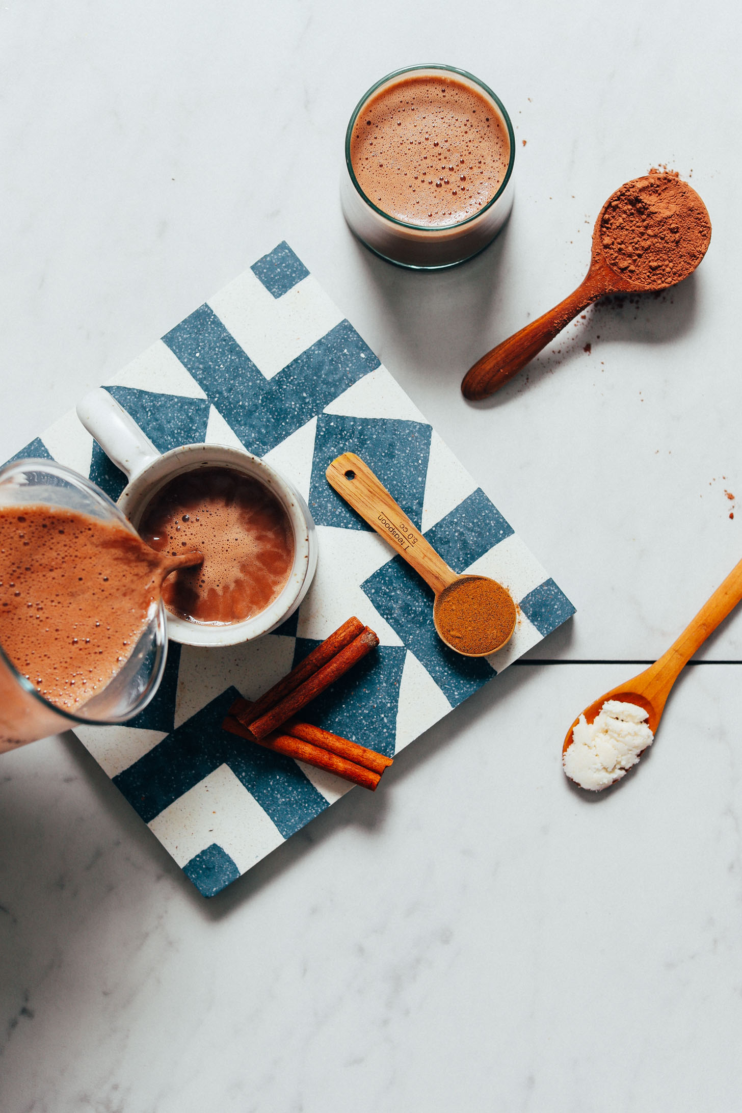 Pouring a mug of our dairy-free Adaptogenic Hot Chocolate recipe beside ingredients used to make it