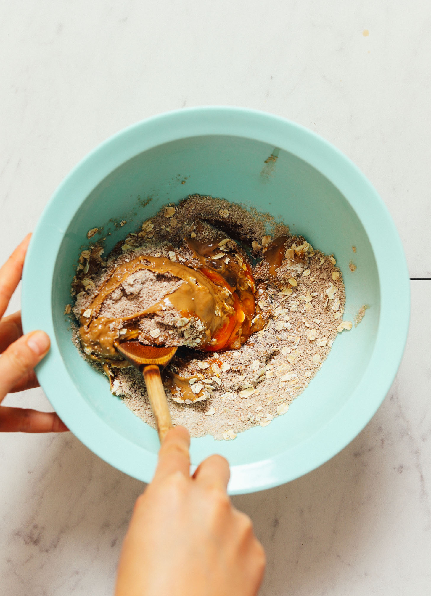 Using a wooden spoon to stir gluten-free Peanut Butter Chocolate Chip Cookie batter