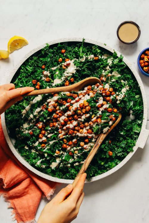 Using salad tongs to pick up a big serving of Massaged Kale Salad