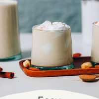 Small and large glass of Easy Vegan Eggnog topped with coconut whipped cream