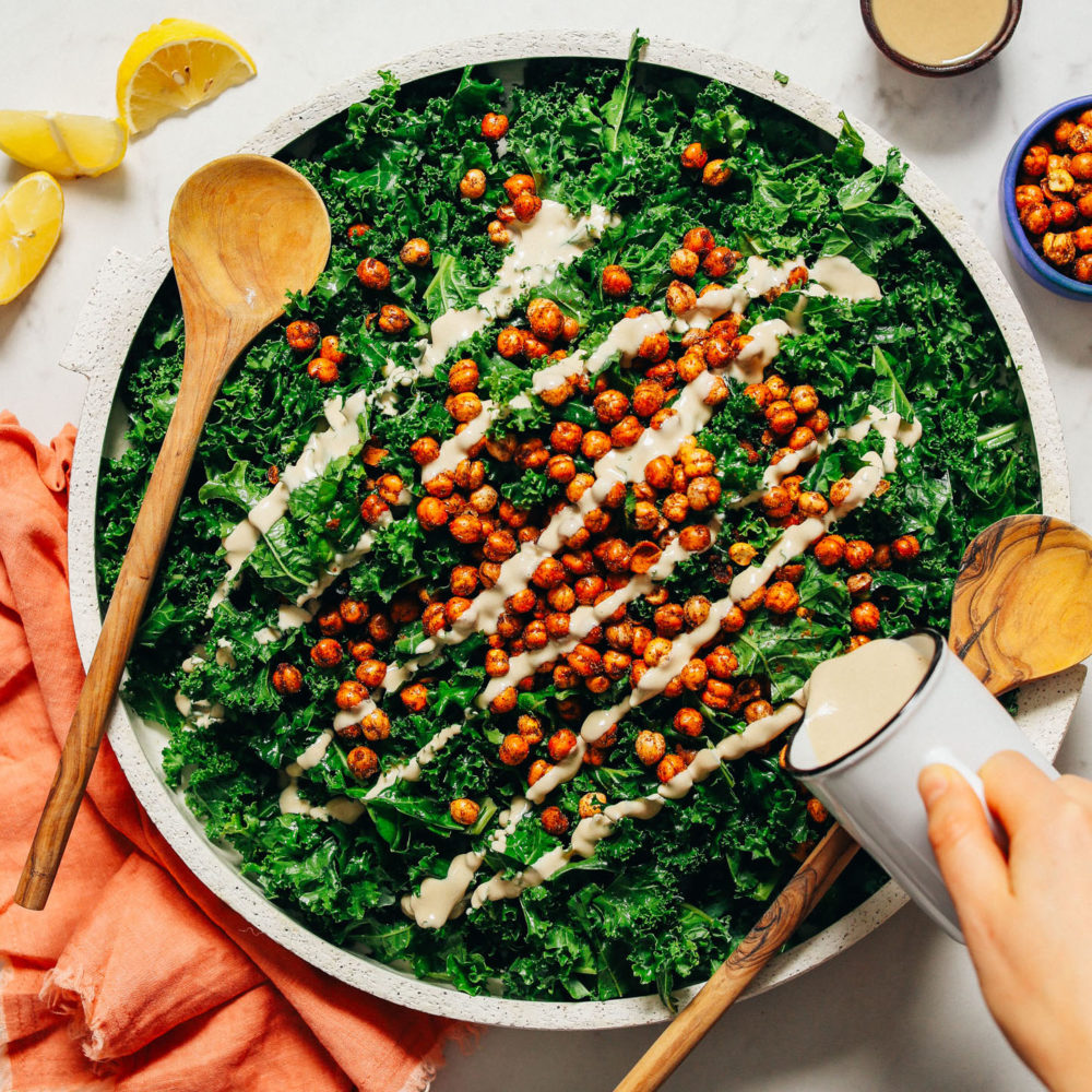 Pouring dressing over a massaged kale salad