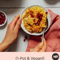 Hands holding the side of a bowl and a spoon of our cozy golden milk porridge recipe