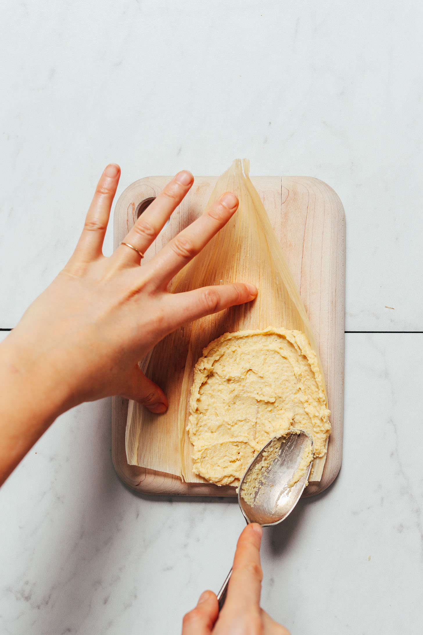 Spreading masa harina mixture onto a dried cornhusk to make tamales