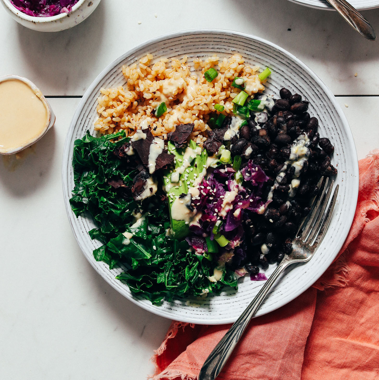 Fork resting in a Black Bean Buddha Bowl topped with Lemon Tahini Sauce