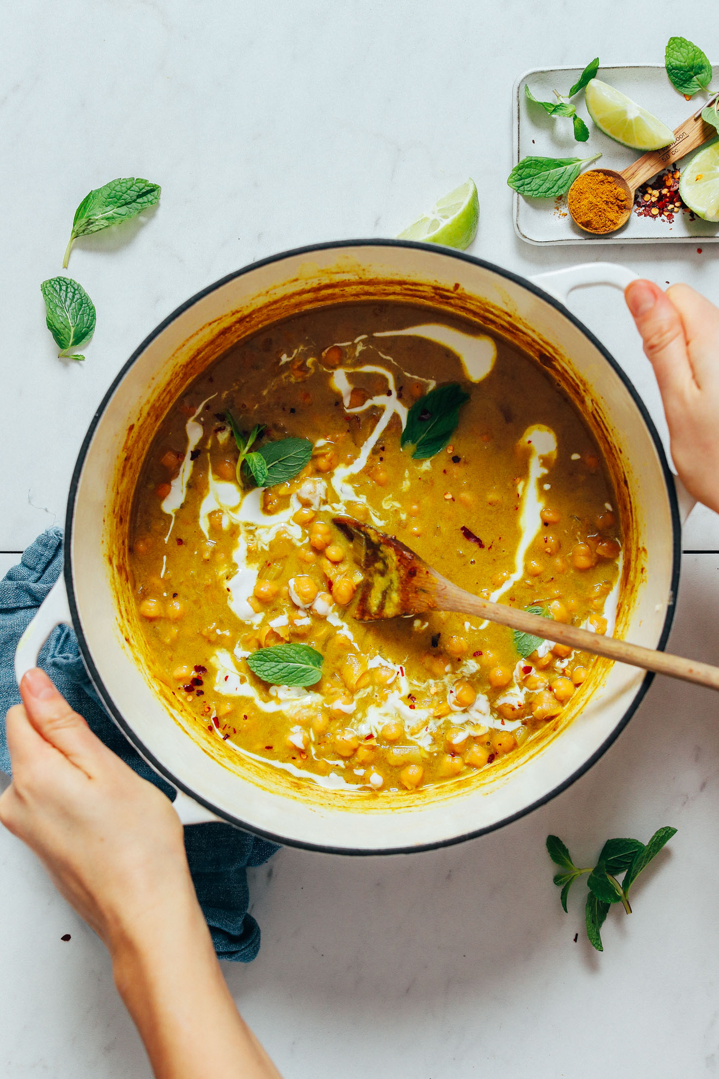 Holding the sides of a pot of Creamy Curried Chickpea Soup topped with fresh mint