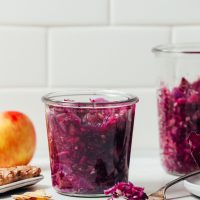 Jar of Apple Cabbage Sauerkraut beside ingredients used to make it