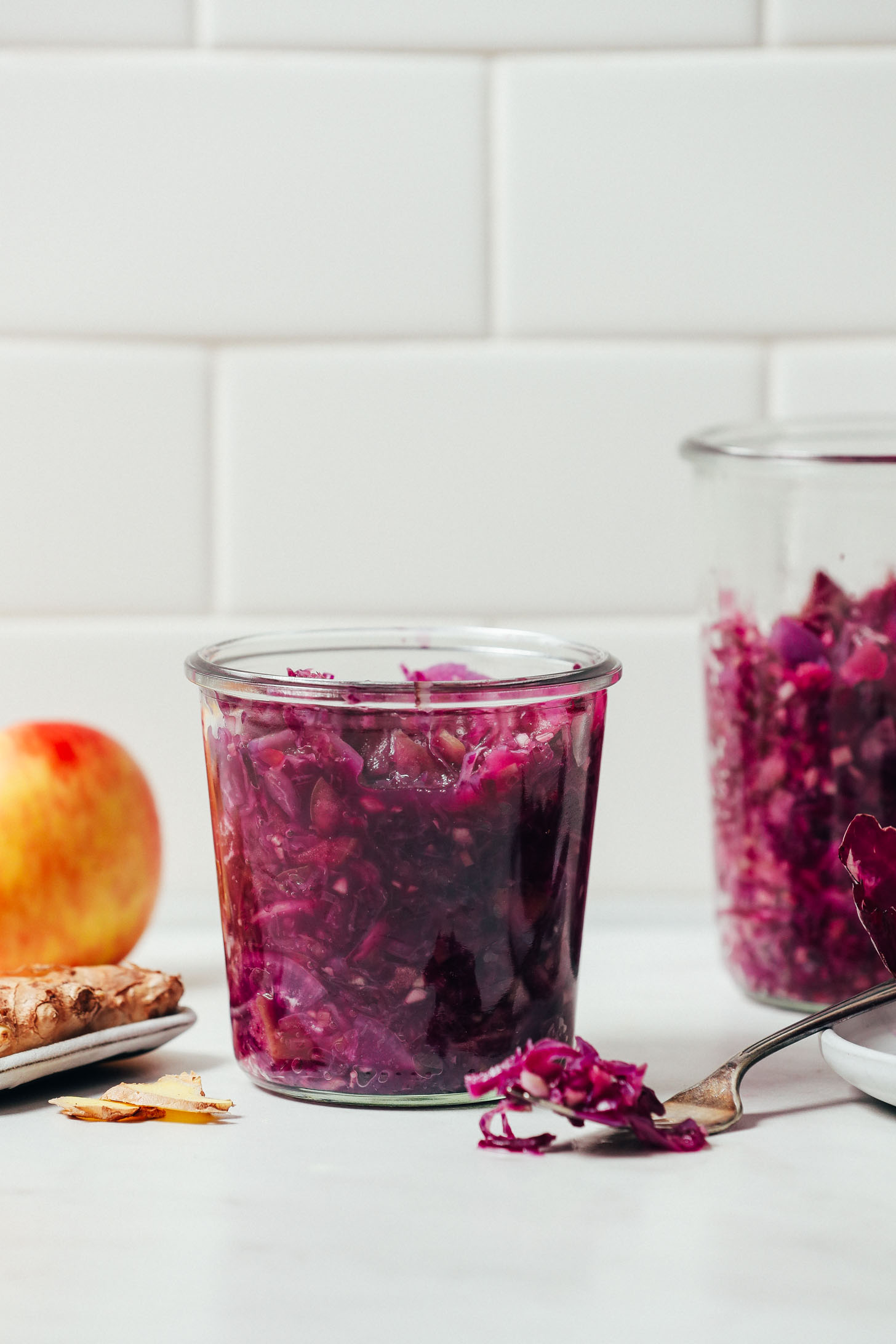 Jar of Apple Cabbage Sauerkraut beside ingredients used to make it