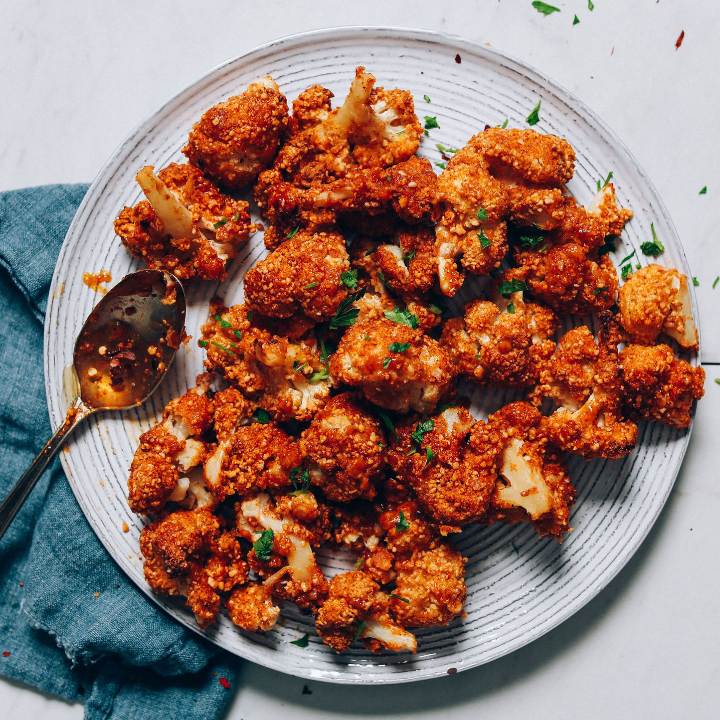 Spoon resting on a plate of Crispy Breaded Cauliflower made with a cashew-based breading