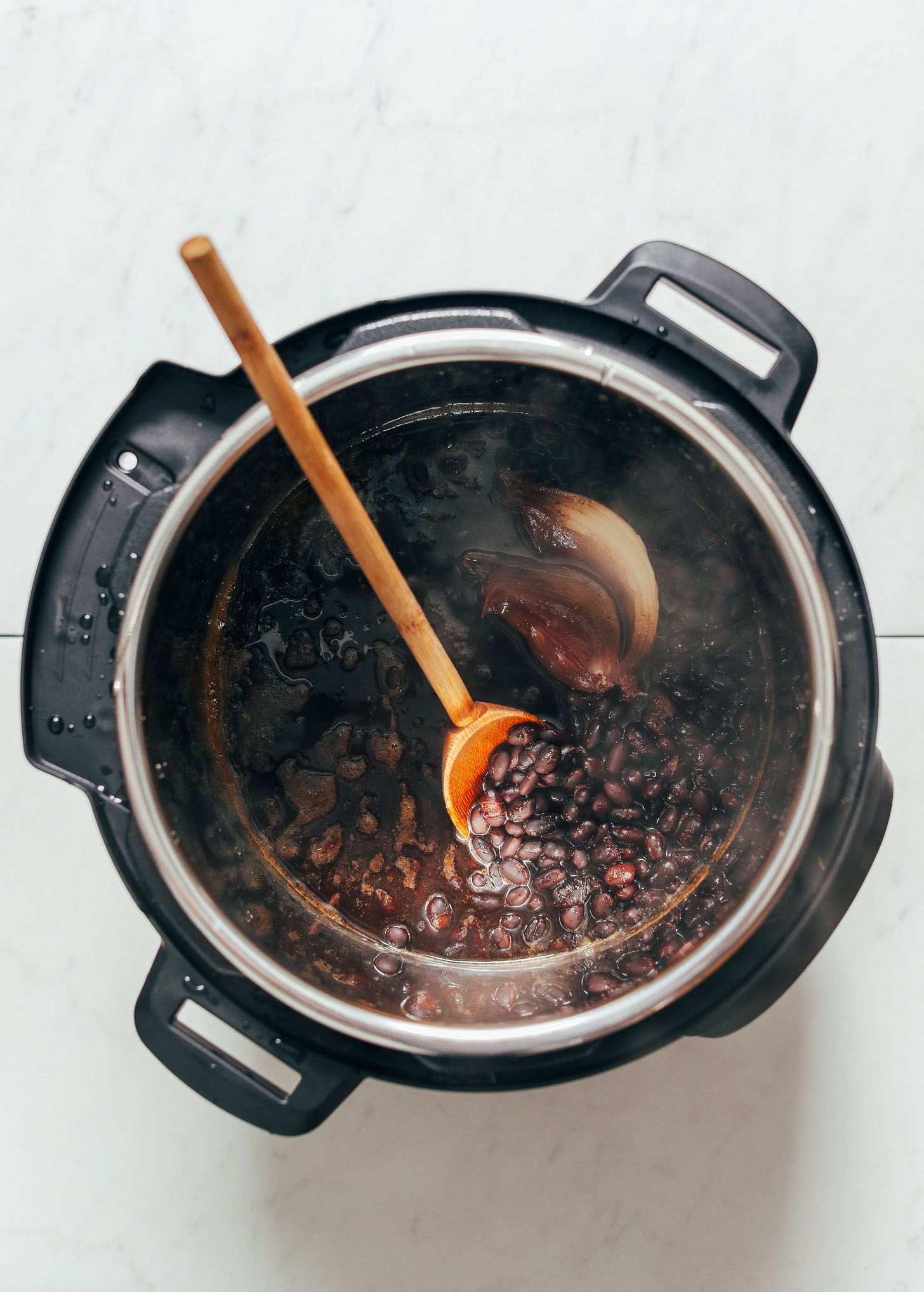 Wooden spoon in a pot of perfectly cooked easy Instant Pot Black Beans