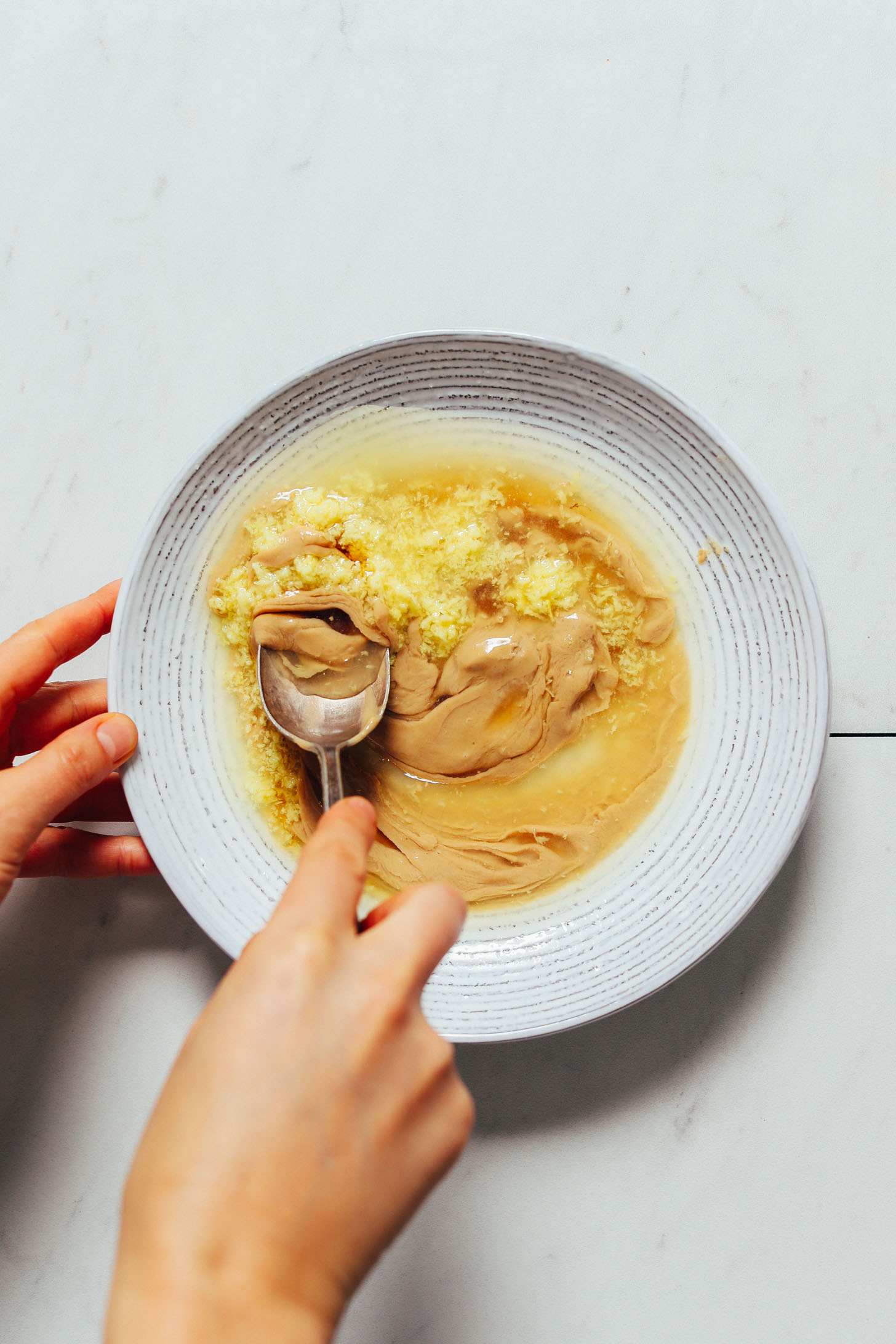 Using a spoon to stir our Lemon Ginger Tahini Dressing