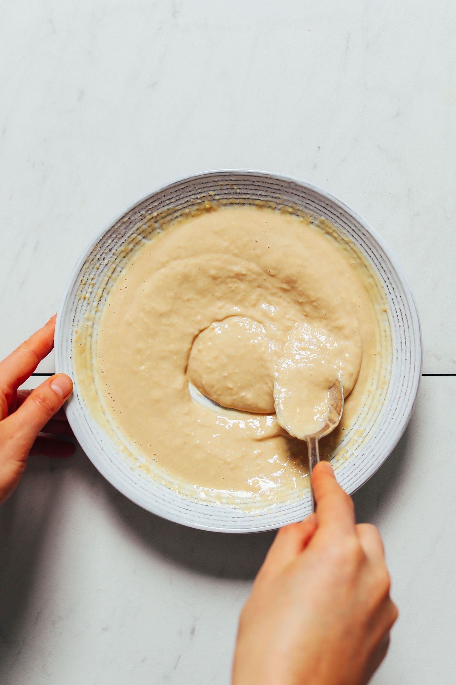 Stirring a bowl of Lemon Ginger Tahini Sauce for topping Buddha bowls