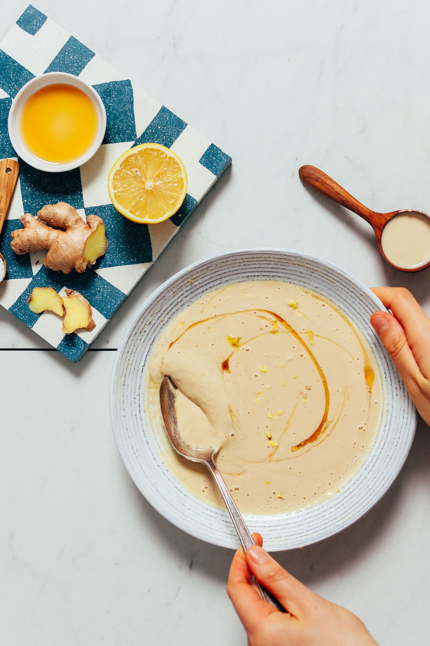 Lemon zest and a swirl of maple syrup in a bowl of our Gingery Lemon Tahini Sauce