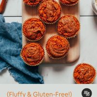 Cutting board filled with a batch of Almond Butter Sweet Potato Muffins beside sliced sweet potato