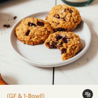 Glass of almond milk beside a plate of gluten-free Peanut Butter Chocolate Chip Cookies