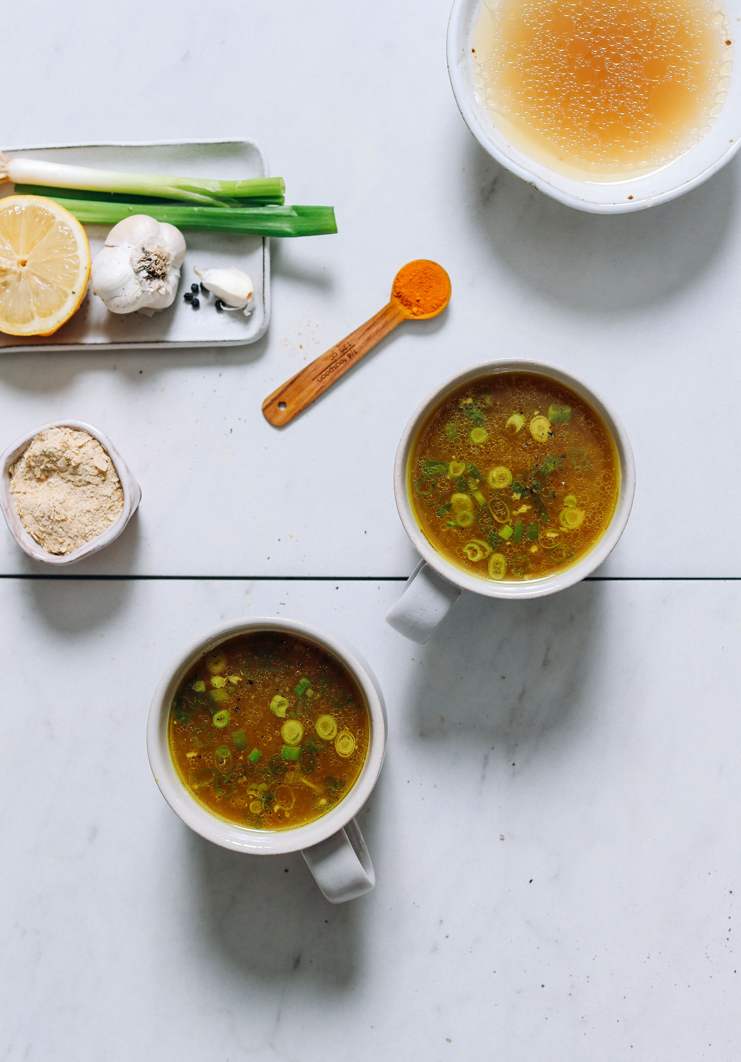 Two mugs of our Chicken Bone Broth Tonic with green onion